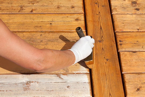 Coloured wood preservative being applied to decking